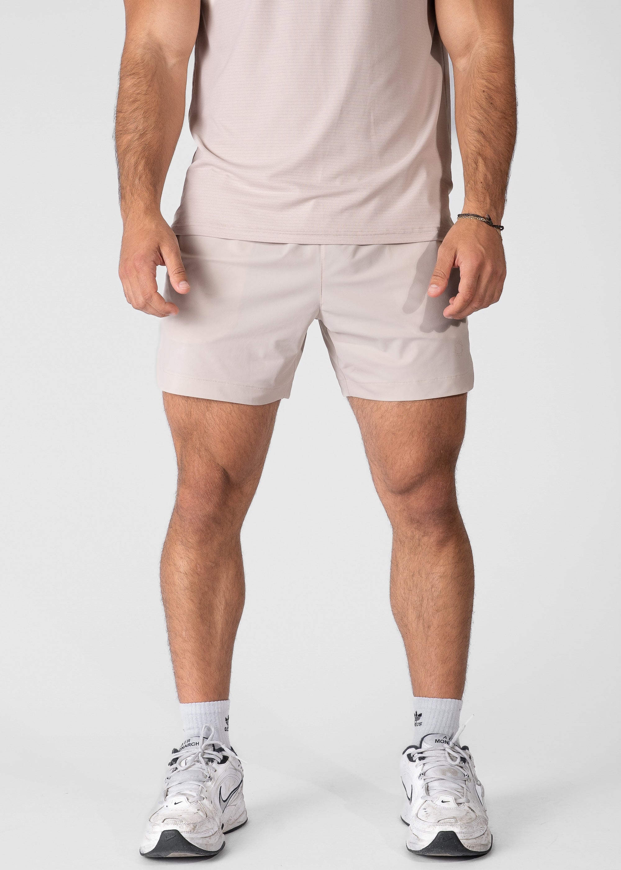 Man wearing atmos grey hybrid shorts on plain background. #color_atmos grey #model_A