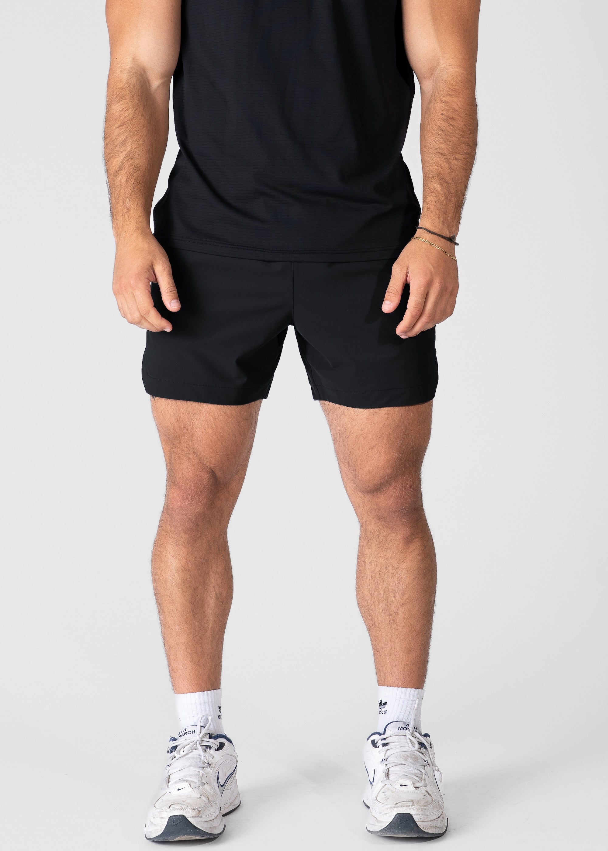 Man wearing black hybrid shorts on plain background. #color_black #model_A