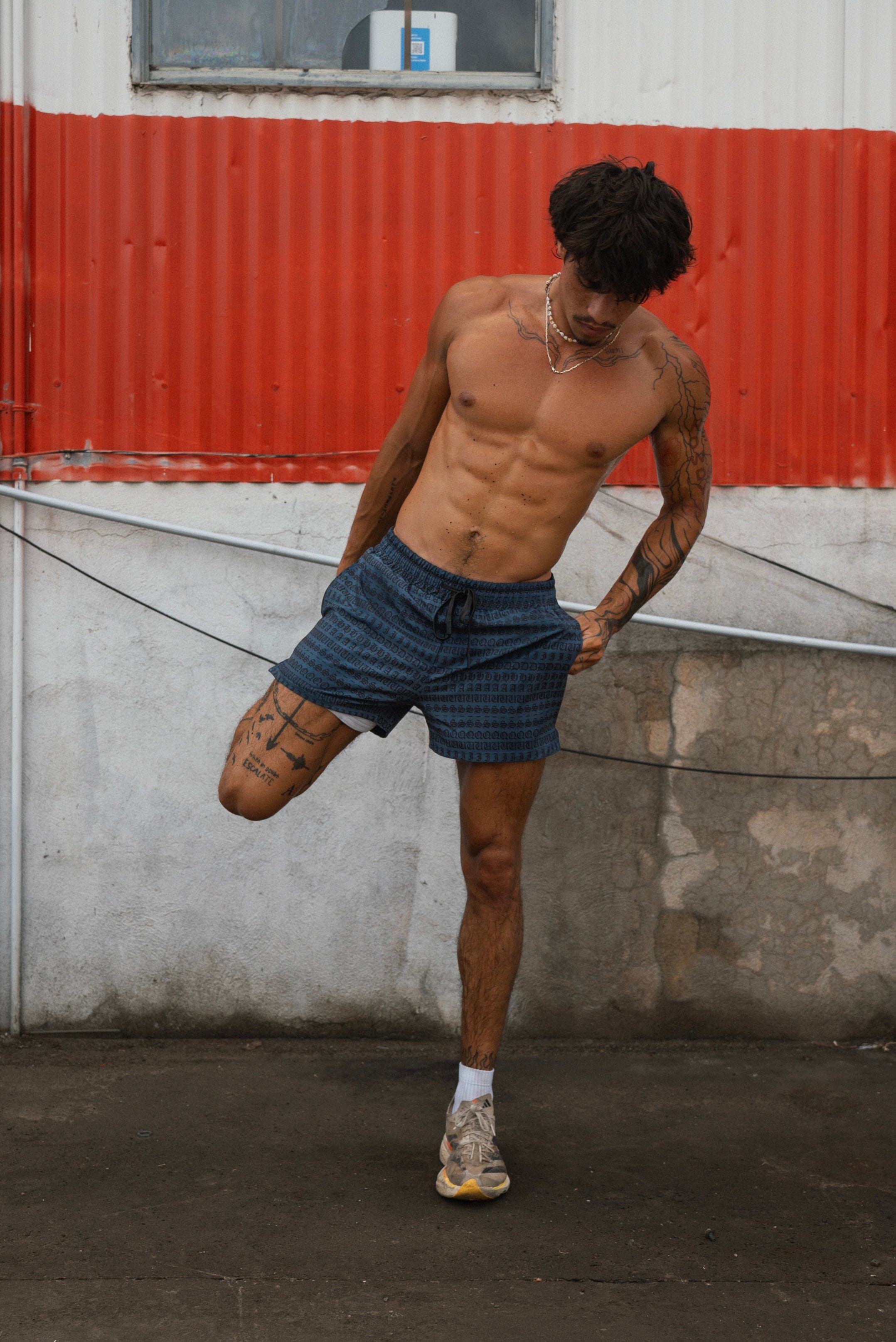 An athlete stretches his hamstring before his run while wearing Squidhaus mesh shorts