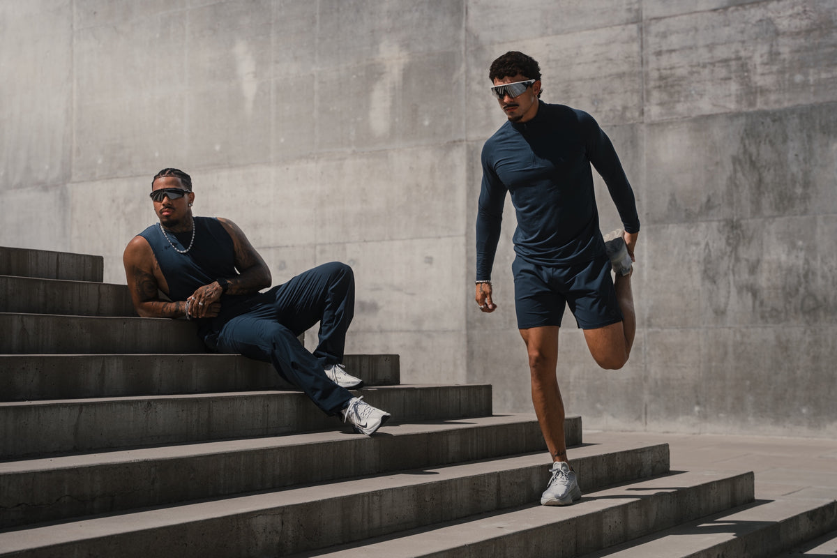 Two athletes in navy HAUS gear on concrete stairs