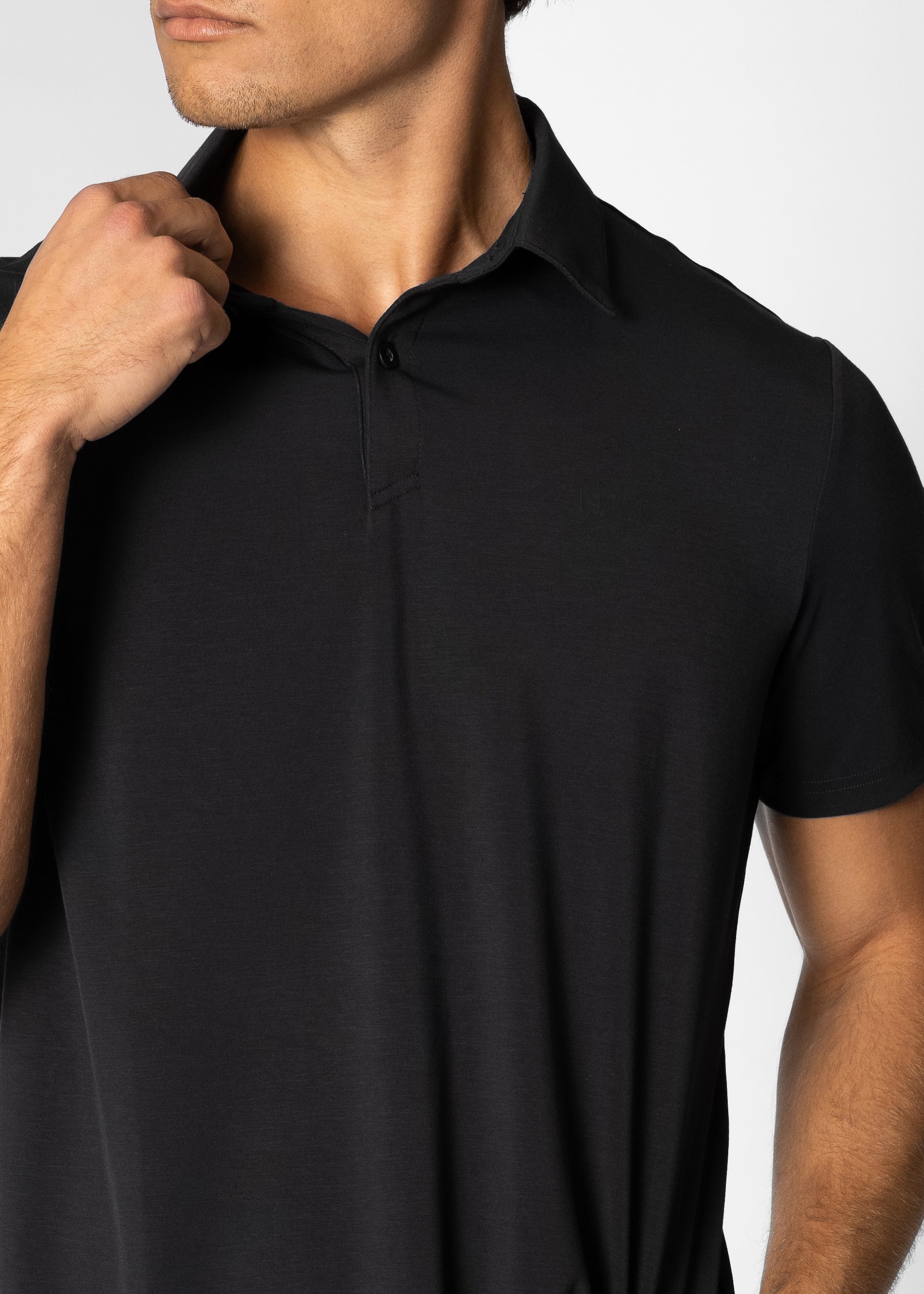 Man wearing a black polo shirt against a white background #color_black