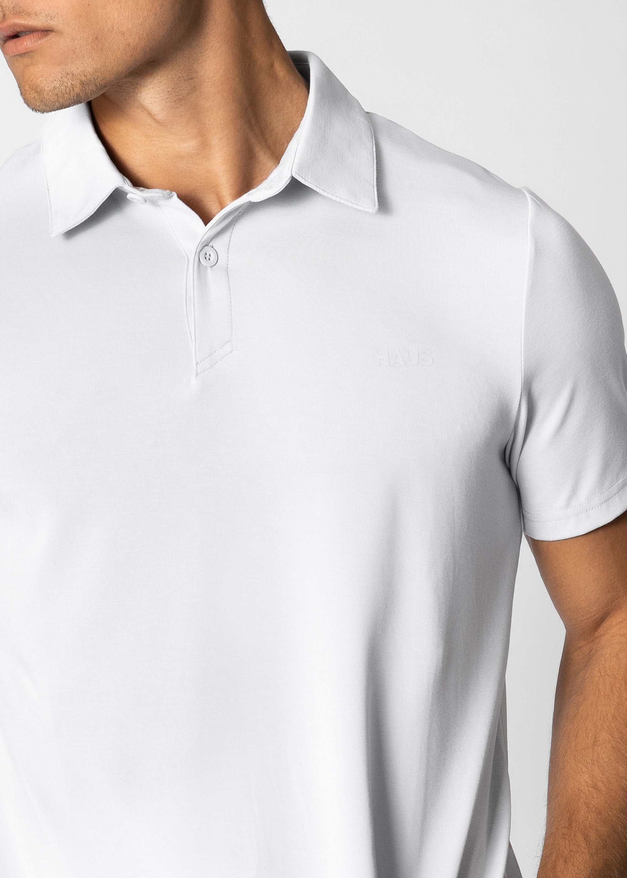 Man wearing a white polo shirt against a plain background #color_white