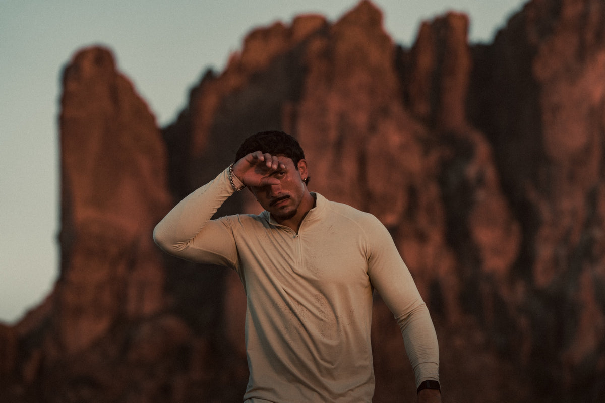 Athlete in a HAUS quarter zip wiping his brow in the desert