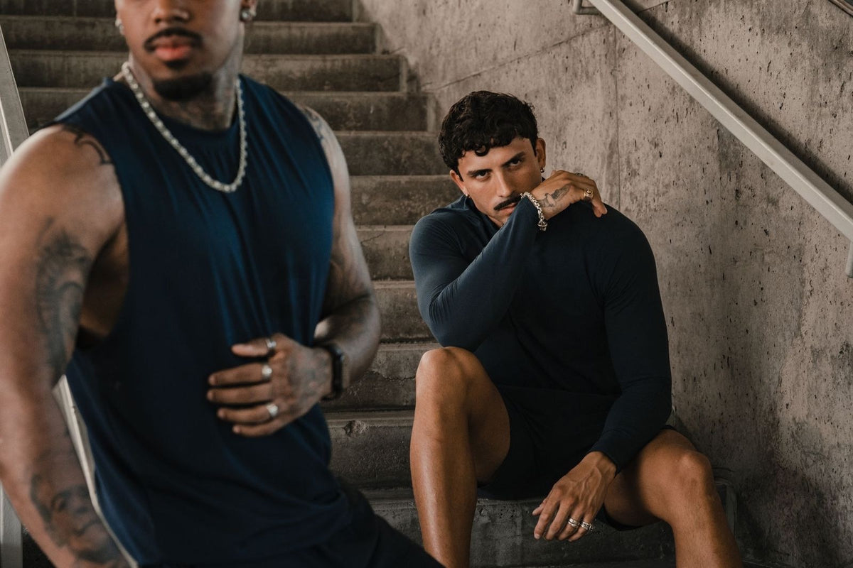 Two Haus athletes on a concrete stairwell in navy training tops and shorts